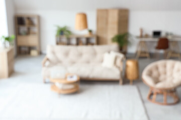 View of blurred living room with sofa, armchair and workplace