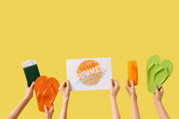 Hands holding two pairs of flip flops passport with tickets, sunscreen spray and paper with text HELLO SUMMER