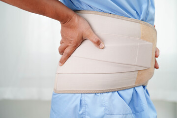Asian senior wearing elastic support belt can help reduce back pain.