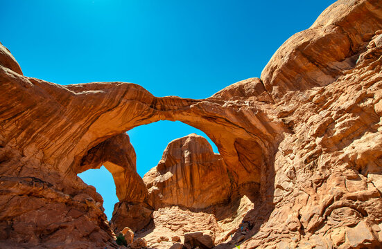 Scenic view of Double Arch red sandstone rocks under clear blue sky in Arches National Park - Powered by Adobe