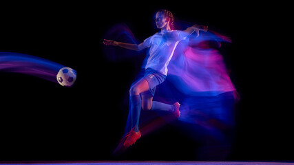 Female football player kicking ball in neon light motion. Concept of sports advertising, athletic performance visuals, football training materials, and activewear promotion.
