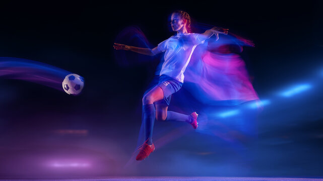 Soccer player kicking ball under blue and pink motion lights at night stadium. Concept of sport branding, fitness advertising, performance coaching visuals, and football product campaigns. - Powered by Adobe