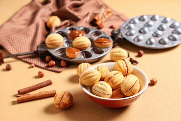 Bowl with tasty walnut shaped cookies with boiled condensed milk on beige table, closeup