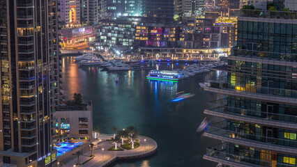 Fototapeta premium Aerial view of Dubai Marina residential and office skyscrapers with waterfront day to night timelapse
