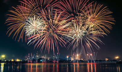 Festive fireworks above city river at night