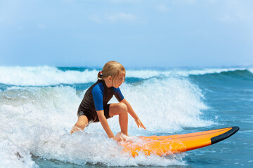 Happy young surfer girl with surfboard have fun on beach, riding on small ocean waves. Summer adventures, active families, parents and kids lifestyle, sports activities on school holiday with kids