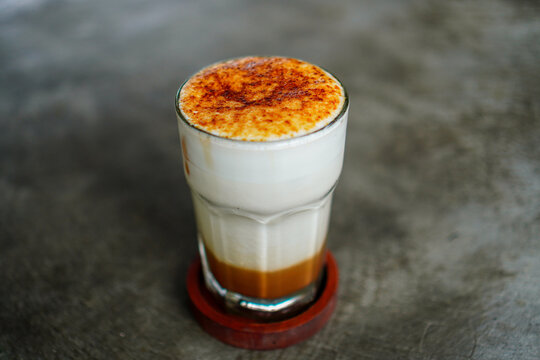 A delectable cr?me br?l?e latte in a clear glass showcases layers of coffee, milk, and a caramelized topping, presenting a modern twist on a classic dessert. The beverage is expertly styled.