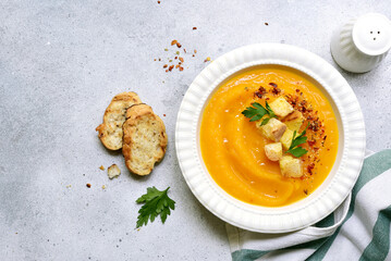 Delicious pumpkin soup with croutons in white bowl . Top view with copy space.