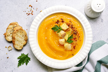 Delicious pumpkin soup with croutons in white bowl . Top view with copy space.