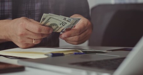 Close-up of man counting dollar bills while planning finances, concept of income, expenses, and savings. - Powered by Adobe