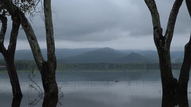 Peaceful 4K footage of Huai Kan Lueang Reservoir wrapped in soft morning mist, showcasing calm water, lush scenery, and tranquil natural beauty.
