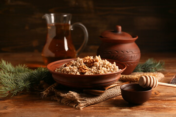 Bowl of traditional Ukrainian Kutya dish with jug of uzvar and Christmas tree branches on wooden...