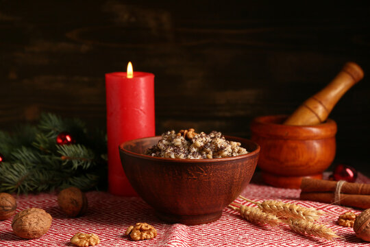 Bowl of traditional Ukrainian Kutya dish with Christmas tree branch and burning candle on wooden background - Powered by Adobe