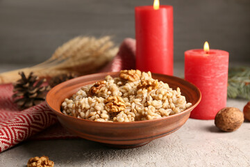 Bowl of traditional Ukrainian Kutya dish and burning candles on white table