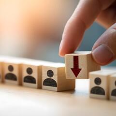 Hand Selecting Wooden Block with Red Arrow Representing Employee Downsizing Business Concept