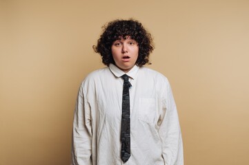 Obraz premium Surprise expression on a person's face with curly hair against a plain background during a casual indoor setting