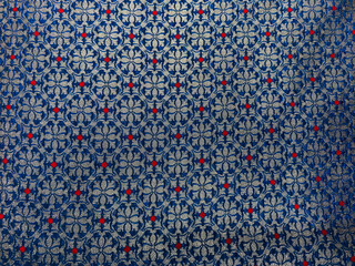 An intricate geometrical floral brocade fabric woven in rich blue and silver threads, showcasing timeless elegance and exquisite craftsmanship.