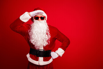 Santa in red costume with white beard and hat saluting against red background for Christmas seasonal stock photo