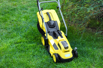 Modern lawn mower on green grass outdoors