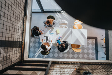 A group of professionals gathers around a table to review charts, documents, and digital devices...