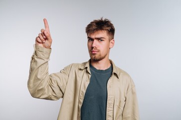 Confident young man pointing upward in a well-lit indoor space during a casual moment