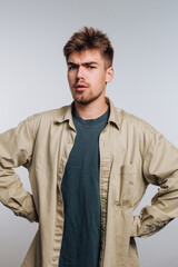 Young man wearing casual clothing poses with a serious expression in a studio setting