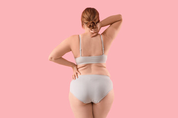 Fototapeta premium Overweight woman in underwear on pink background, back view