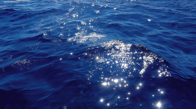 Shimmering blue ocean water surface illuminated by bright sunlight creating sparkling reflections and a sense of tranquility and serenity in nature's beauty