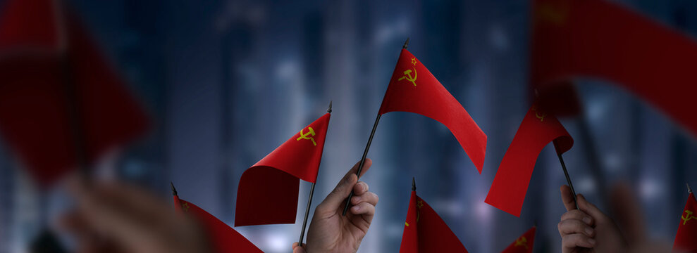 USSR flags in their hands on a blurred urban background