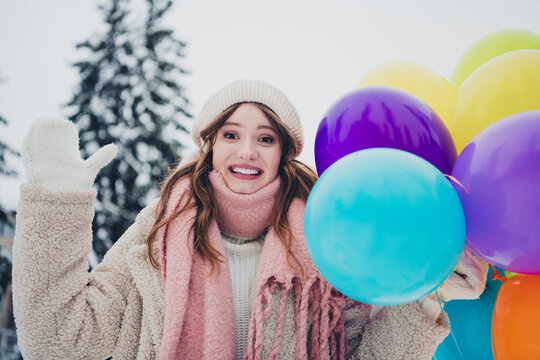 Smiling Woman Outdoors Holding Colorful Balloons on a Snowy Winter Day