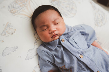 Cute newborn baby boy sleeping peacefully in white crib and soft nest. Close-up of infant resting on bed, symbolizing childhood innocence, comfort, and family love. Perfect for baby care themes.