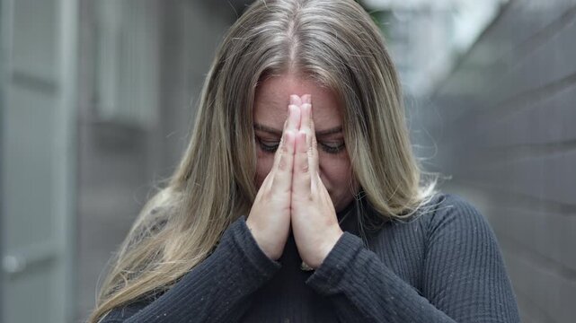 Woman Bowing Head With Hands In Prayer Pressed Together In Front Of Face Standing In Contemplative Posture During Quiet Spiritual Moment