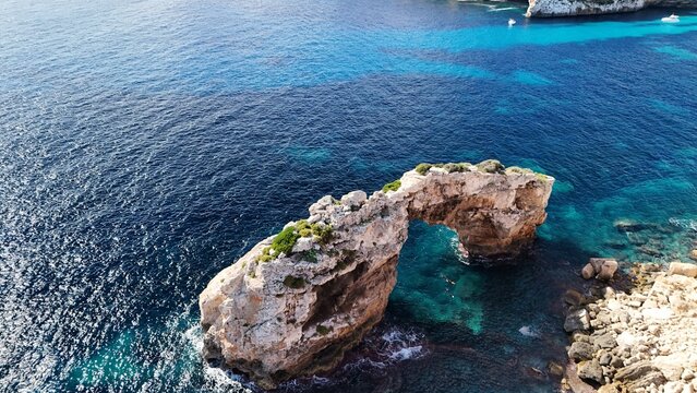 Luftaufnahme des Felsbogens Es Pont&agrave;s an der S&uuml;dk&uuml;ste von Mallorca &ndash; nat&uuml;rliche Felsbr&uuml;cke &uuml;ber dem t&uuml;rkisblauen Mittelmeer, Balearen, Spanien