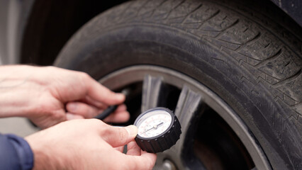 Mechanic checking car tire pressure with gauge