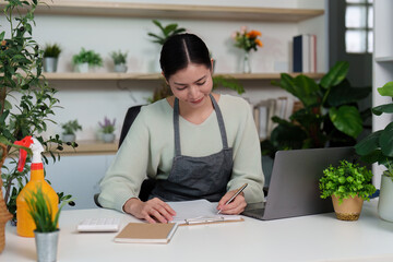 Remote Work. Young woman writing notes at home office desk with laptop.