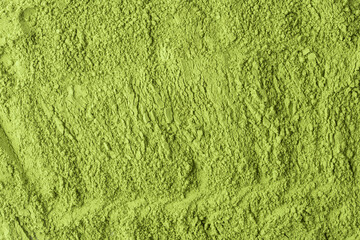 Textured surface of vibrant green matcha powder with uneven clusters creates a natural and organic visual background.