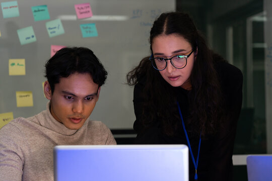 Business team analyzing data on laptops with growth chart in background. Diverse professionals collaborating in office, discussing financial performance, strategy, and success analytics in workplace.