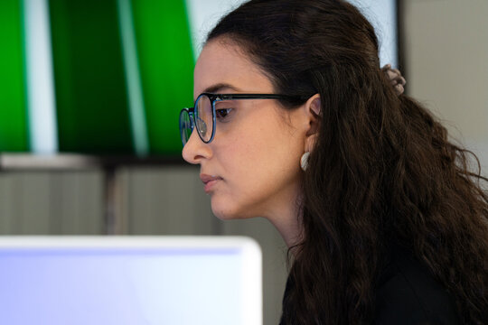 Focused businesswoman working on computer in modern office. Professional female analyzing data and concentrating on project tasks, representing productivity, technology, and corporate success.