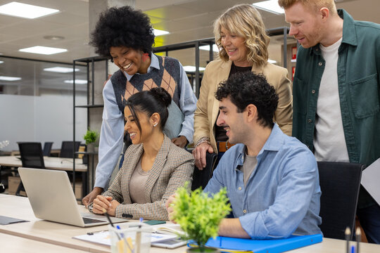 Diverse business team collaborating using laptop in office