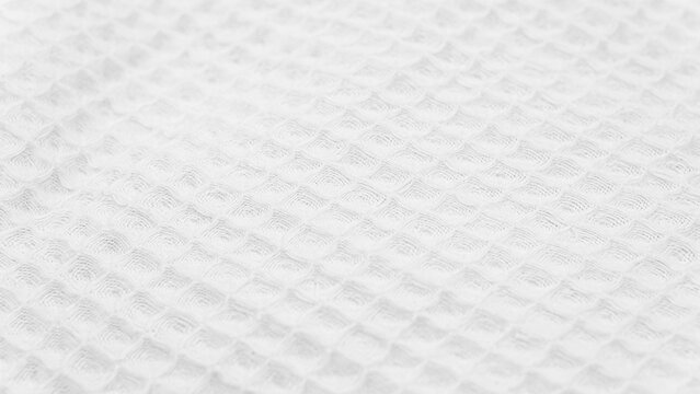 White woven textile blanket texture with soft waffle pattern, clean minimal fabric background for bedding, spa or textile design concepts.