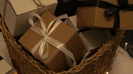 Christmas gift boxes arranged in a woven basket, camera pans down revealing festive decorations and warm ambiance. Parcel christmas concept - Powered by Adobe