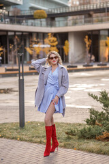 Naklejka premium Portrait of a young blonde woman in a red hat and boots on an autumn walk in the city