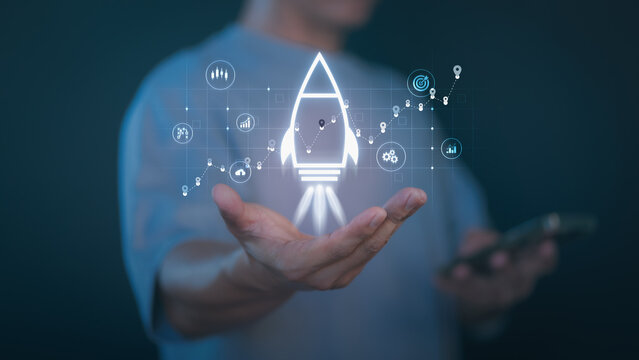 Person holding a glowing rocket icon with digital analytics, graph, and startup symbols representing business growth, innovation, startup launch, success strategy, and digital marketing development.