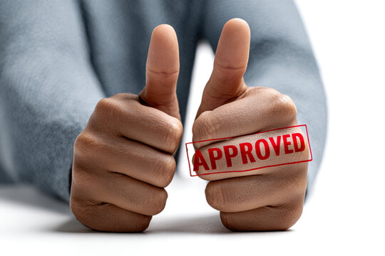 A pair of hands giving two thumbs up, featuring an "APPROVED" stamp on one hand, conveying positivity and approval.