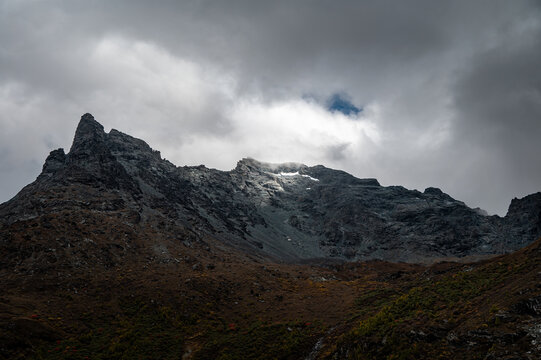 Sunlight pierces through the clouds, illuminating some of the high-altitude peaks