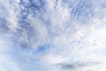 Beautiful gentle light blue sky with many little small fluffy white clouds in sunlight background texture