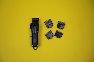 Compact electric trimmer with multiple detachable combs arranged around it on a yellow surface, ideal for grooming, beard shaping, and precise hair cutting.