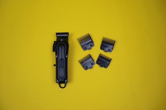 Compact electric trimmer with multiple detachable combs arranged around it on a yellow surface, ideal for grooming, beard shaping, and precise hair cutting.