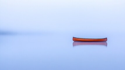 A solitary red canoe resting on a vast tranquil blue lake surface under soft light