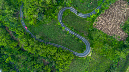 Aerial view of winding road in Malang, East Java, Indonesia surrounded by tropical green hills